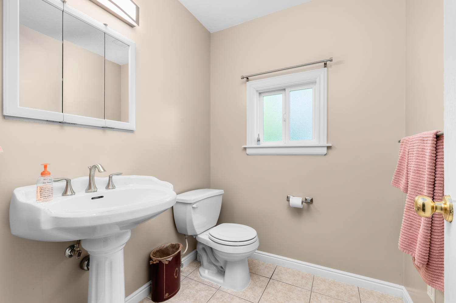 Powder room featuring a pedestal sink with brushed nickel fixtures, a functional window, and tiled flooring