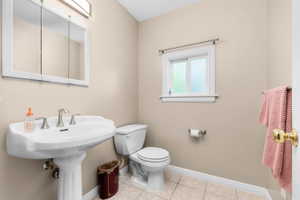 Powder room featuring a pedestal sink with brushed nickel fixtures, a functional window, and tiled flooring