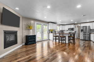 Open-concept living space featuring wood-finish flooring, recessed lighting, and a built-in fireplace
