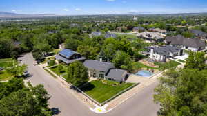 Corner lot property featuring a light green exterior with white trim, a dark gray shingle roof, and a meticulously manicured lawn