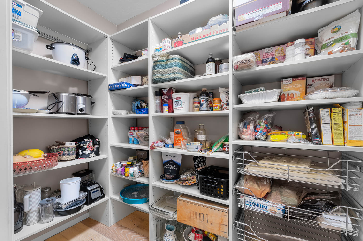 Spacious pantry featuring white built-in shelving, providing extensive storage options
