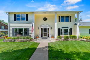 Two-story home with a light-colored exterior and black shutters