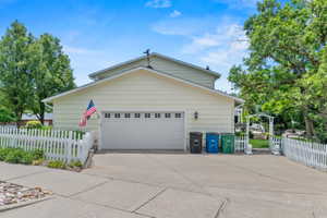 Exterior featuring light yellow siding, a two-car garage with paneling and window inserts, and a concrete driveway