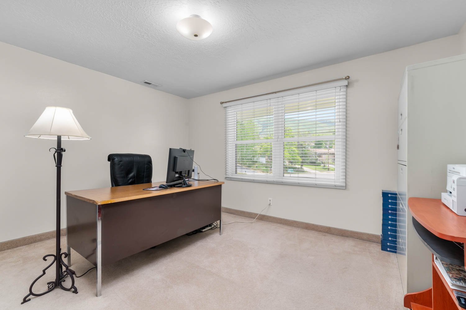 Carpeted room with a ceiling-mounted light fixture, a window with horizontal blinds, and neutral wall paint