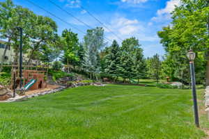 Expansive lawn area featuring established trees and a rock-lined border