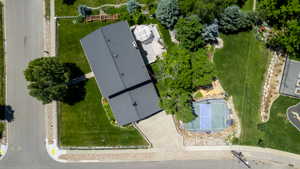 Expansive property featuring a multi-sport court, substantial green spaces, mature trees, and a tiered rock landscaping