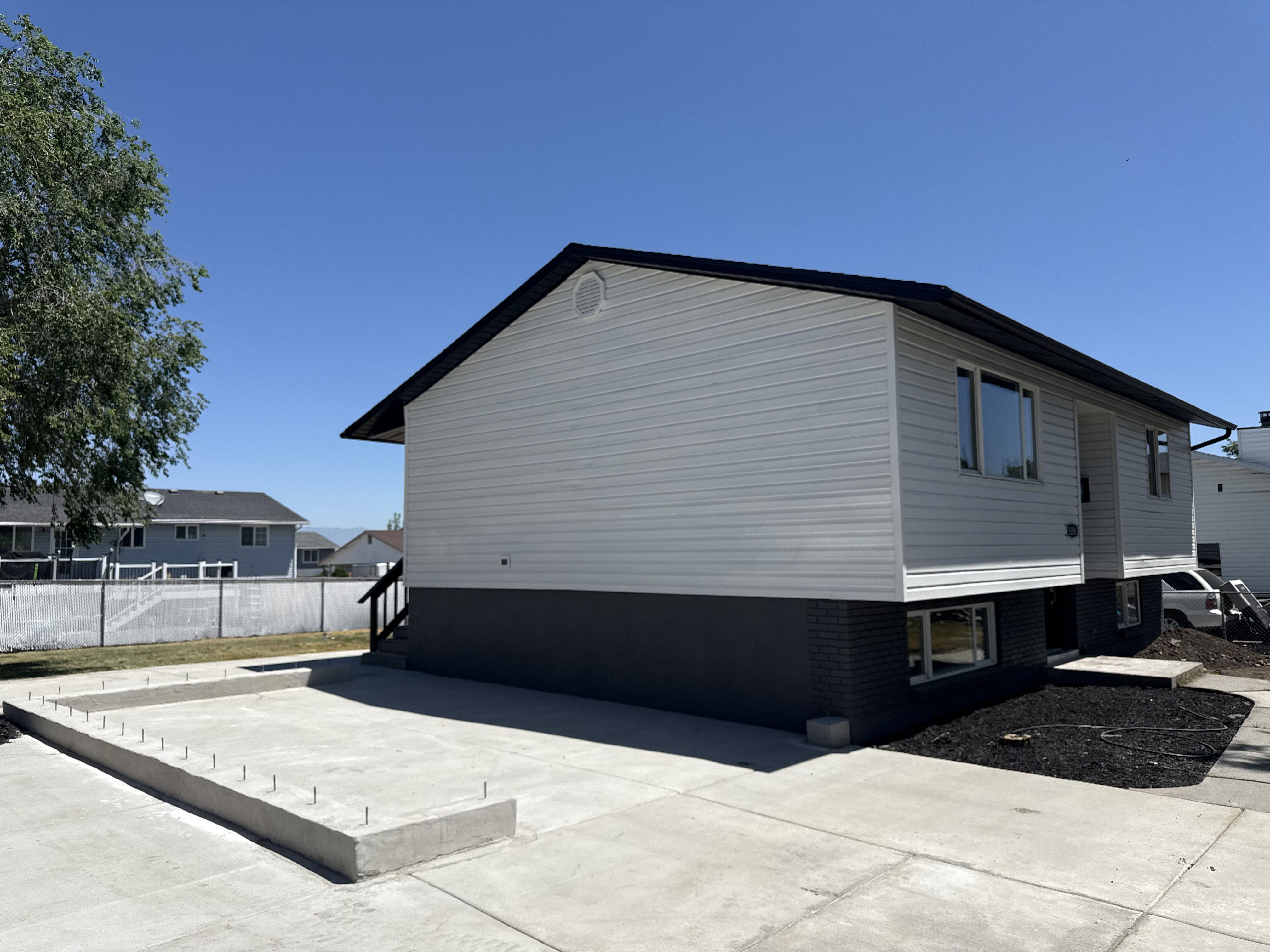 Exterior featuring light gray siding, dark gray brick foundation, and a contrasting dark roofline