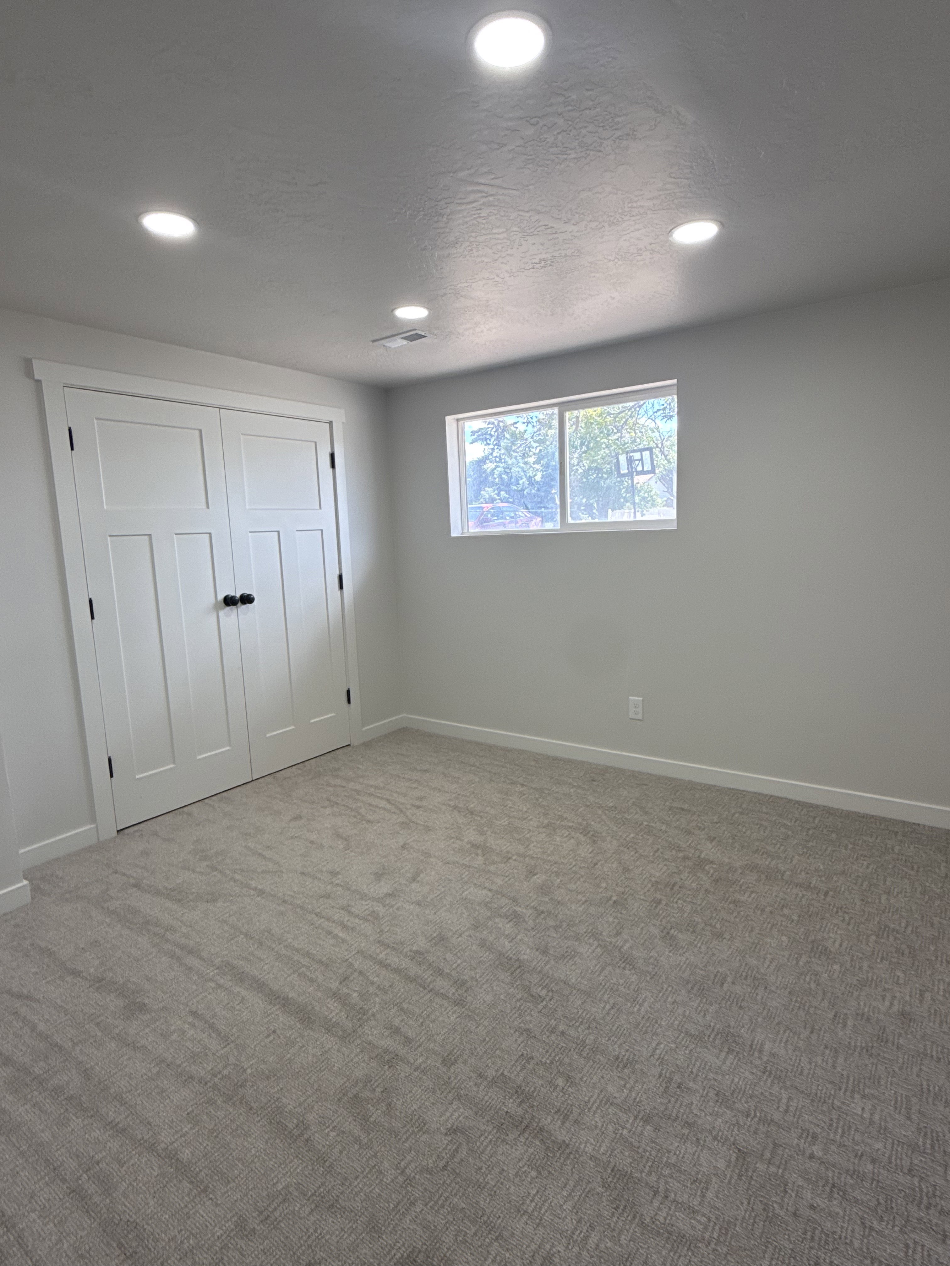 Neutral wall tones complemented by recessed lighting and a window with exterior views