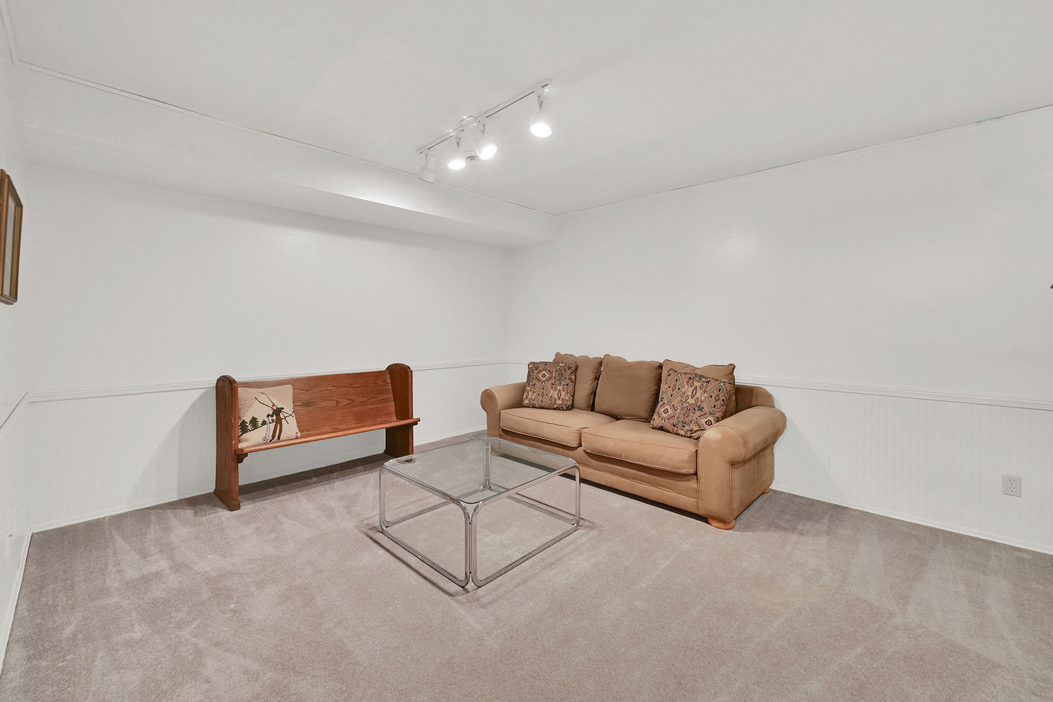 Carpeted room with white walls and track lighting