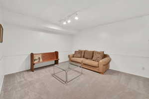 Carpeted room with white walls and track lighting