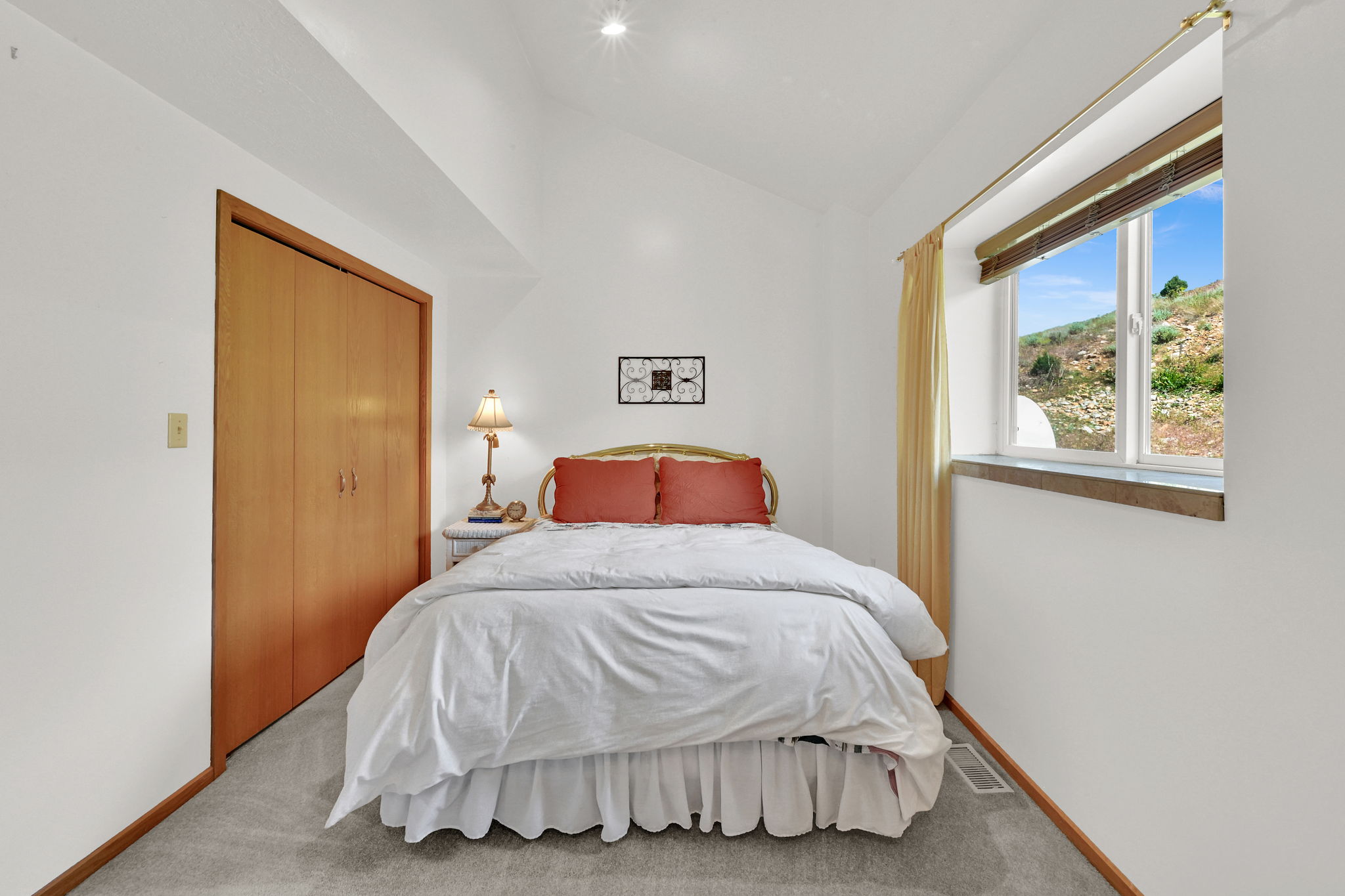 Vaulted ceiling room featuring a large window with exterior scenery, light-toned wood-finish bi-fold closet doors, recessed lighting, and grey carpet
