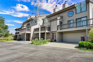 Multi-level exterior featuring horizontal siding, integrated garages, private balconies with wood railings, and a prominent round window