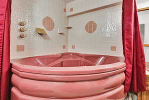 Corner soaking tub with integrated seating, surrounded by tiled walls featuring accent squares and octagons