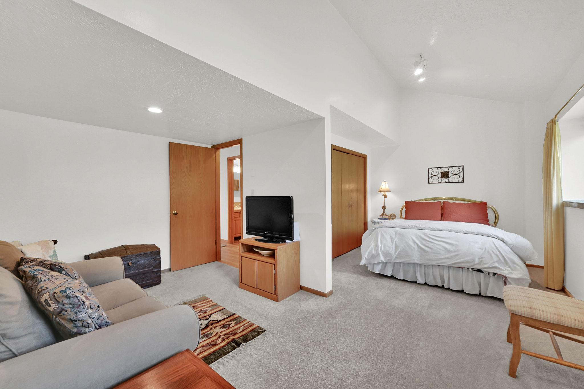 Carpeted interior space featuring a distinct sleeping area and a separate living area
