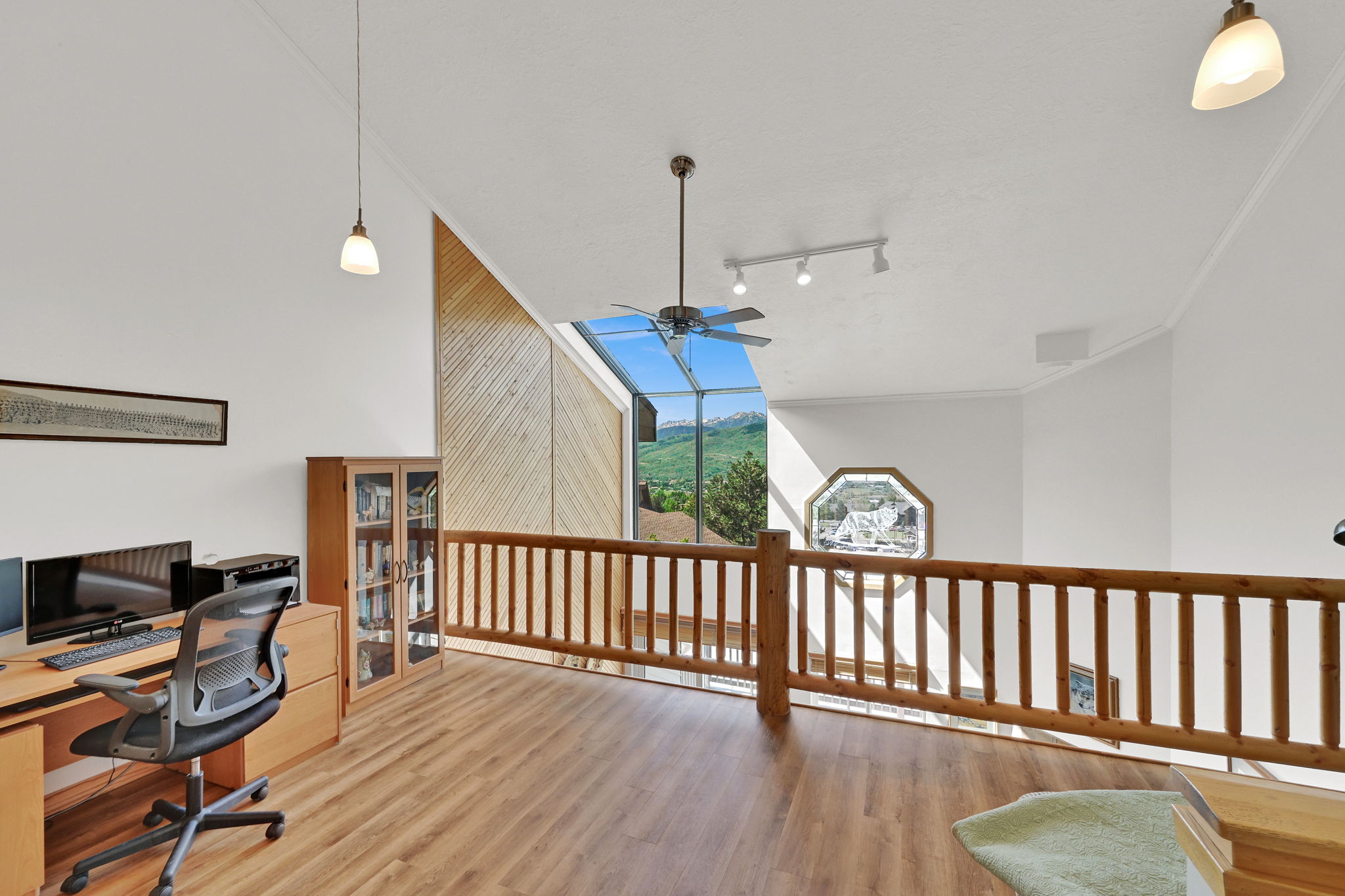 Loft area featuring wood-finish flooring, a wood baluster railing, sloped ceilings, and clerestory windows