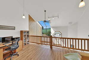 Loft area featuring wood-finish flooring, a wood baluster railing, sloped ceilings, and clerestory windows