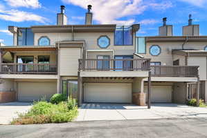 Multi-level exterior featuring tan siding, brown trim, and multiple balconies with dark wood railings