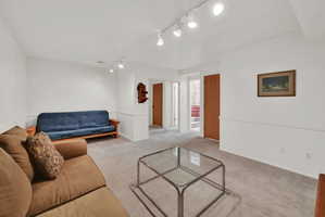 Carpeted room featuring white walls with wainscoting, track lighting, and wood-finish doors