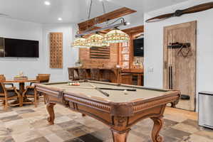 Game room with slate tile flooring and a built-in wet bar featuring stone countertops