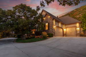 Stucco and stone facade home featuring a two-car garage with arched entrances and exterior sconce lighting