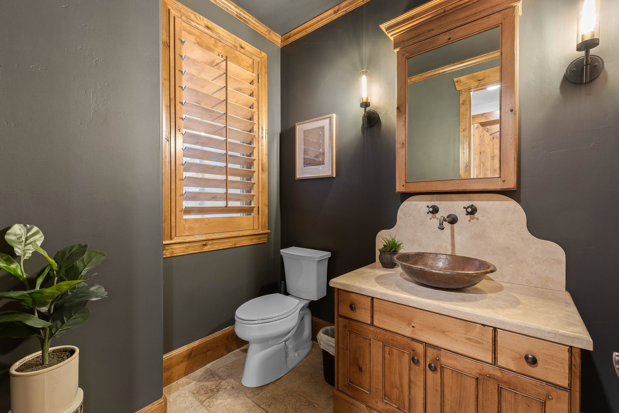 Custom wood vanity with a decorative vessel sink and wall-mounted faucet, complemented by a light-colored countertop