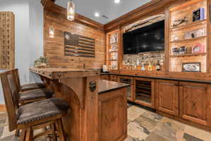 Custom bar area featuring rich wood cabinetry and paneling