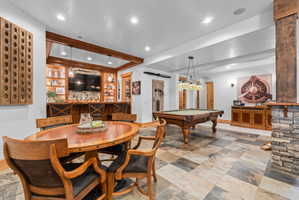 Entertainment space featuring checkerboard tile flooring, a built-in wet bar with wood cabinetry, recessed lighting, and a stone-clad structural column