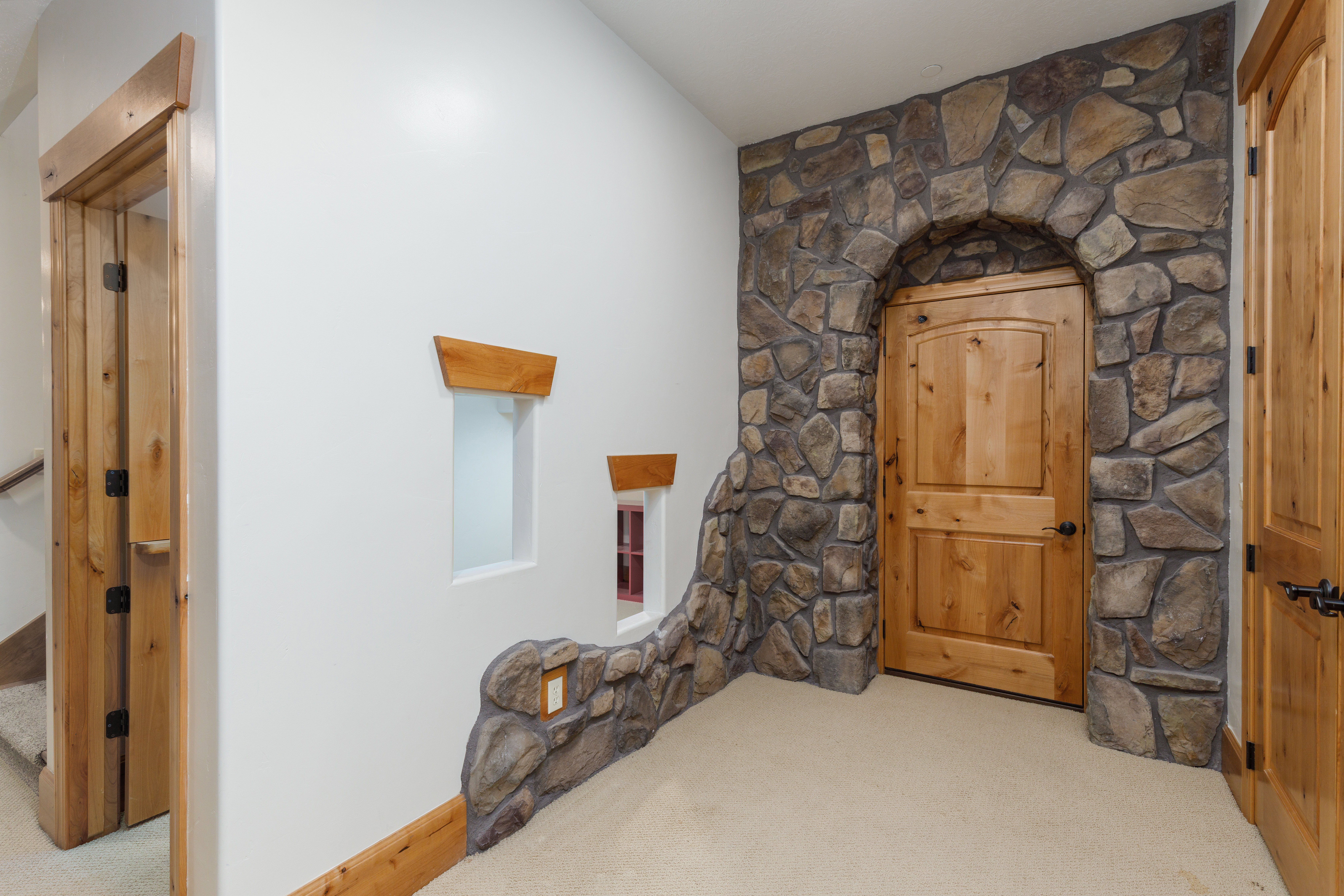 Stone archway entry featuring a solid wood door with dark hardware