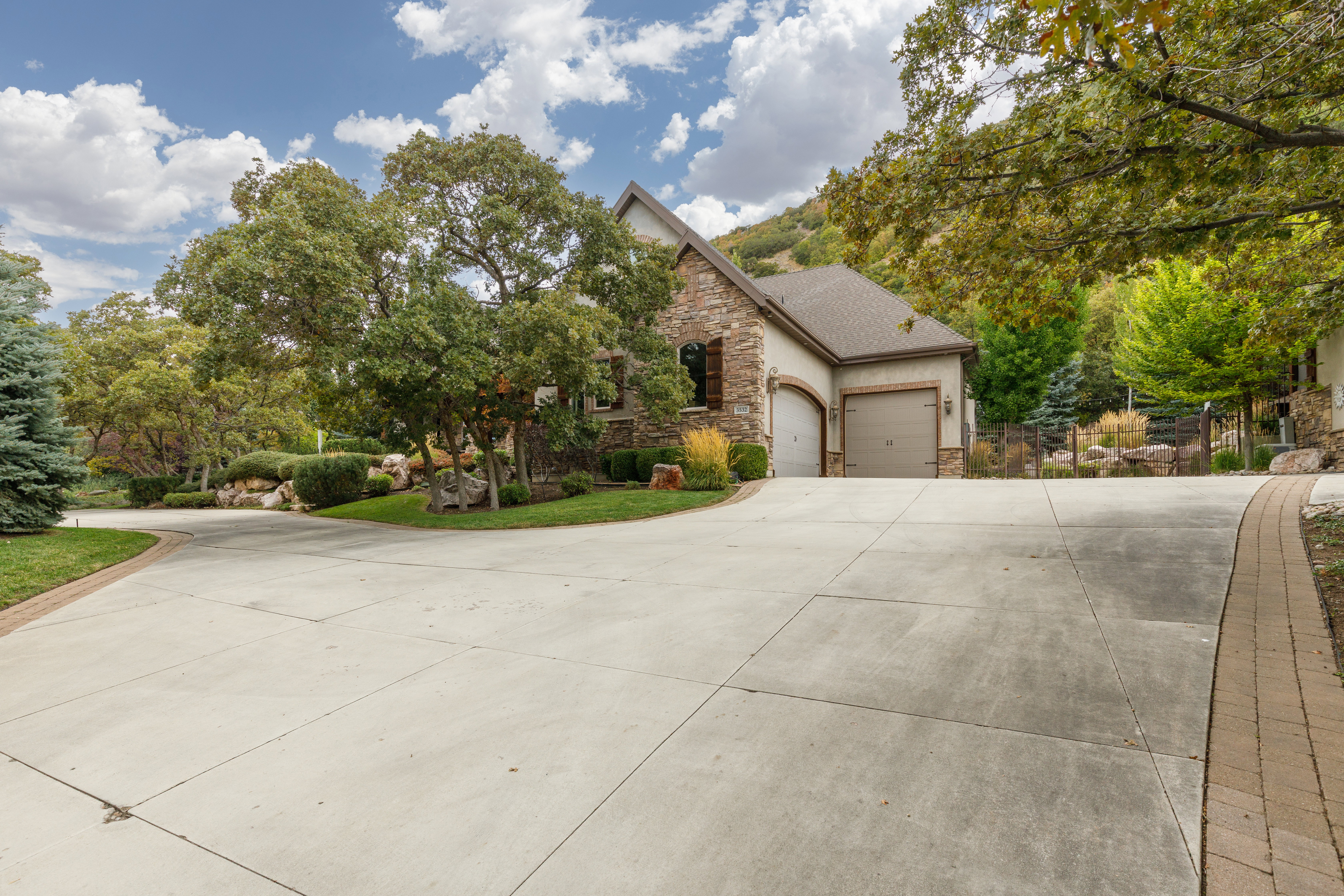 Concrete driveway leading to a stone and stucco exterior with an attached two-car garage