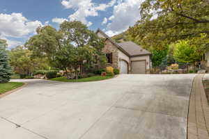 Concrete driveway leading to a stone and stucco exterior with an attached two-car garage