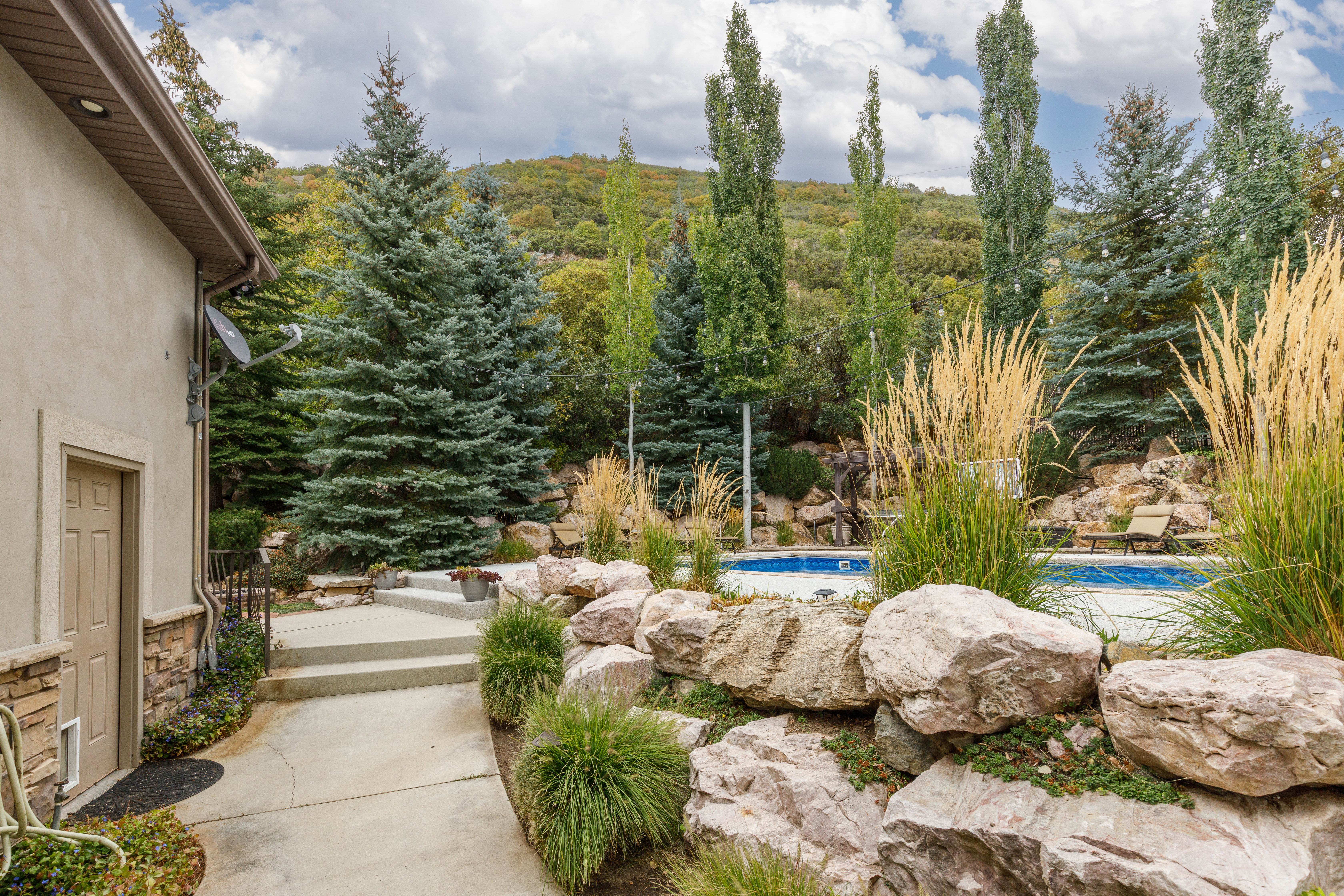 Outdoor private pool area featuring a natural rock wall and mature landscaping