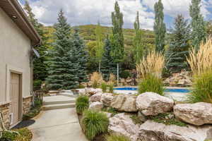 Outdoor private pool area featuring a natural rock wall and mature landscaping