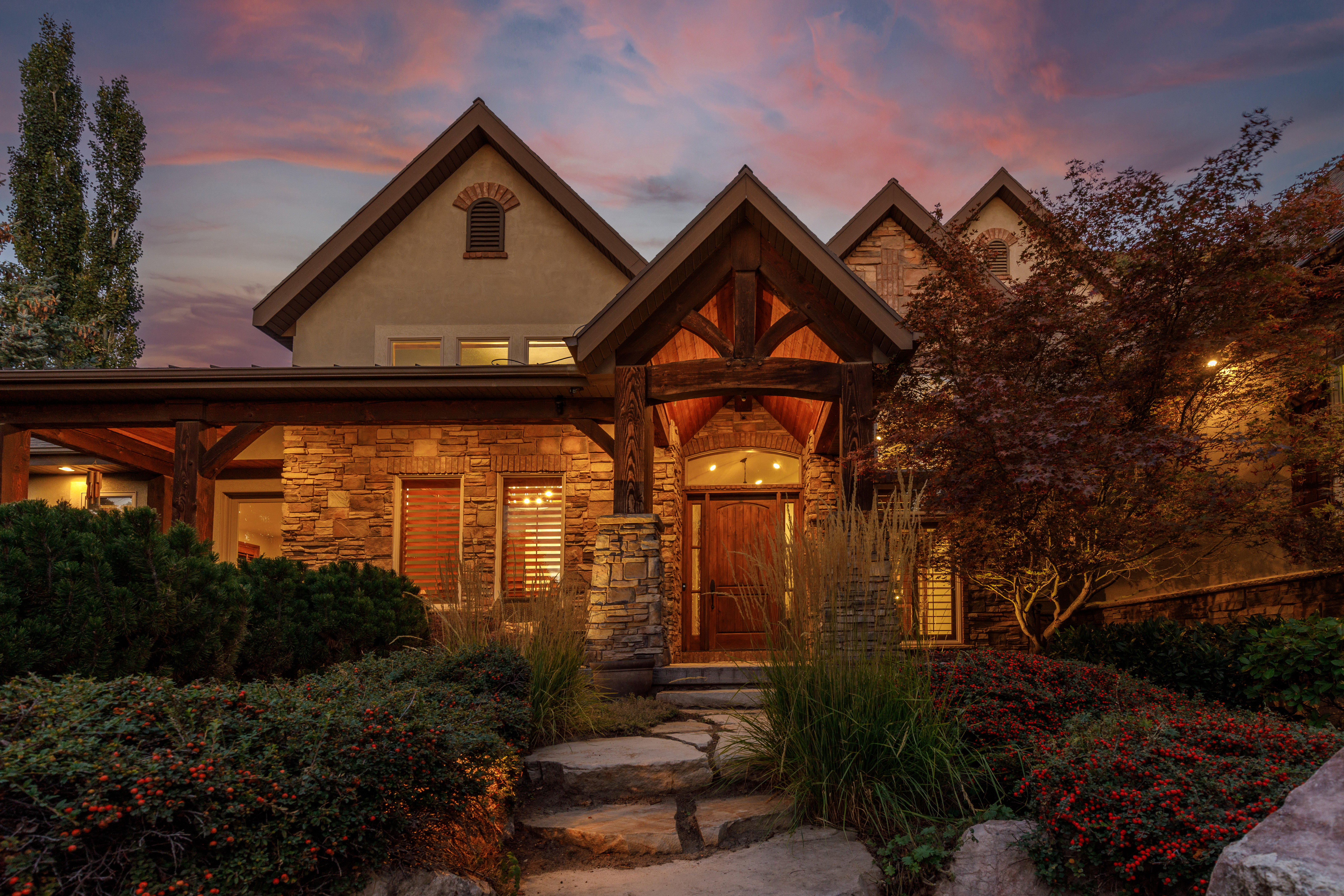 Stone and stucco exterior featuring a prominent timber-frame entry, wood-finish front door, and natural stone walkway