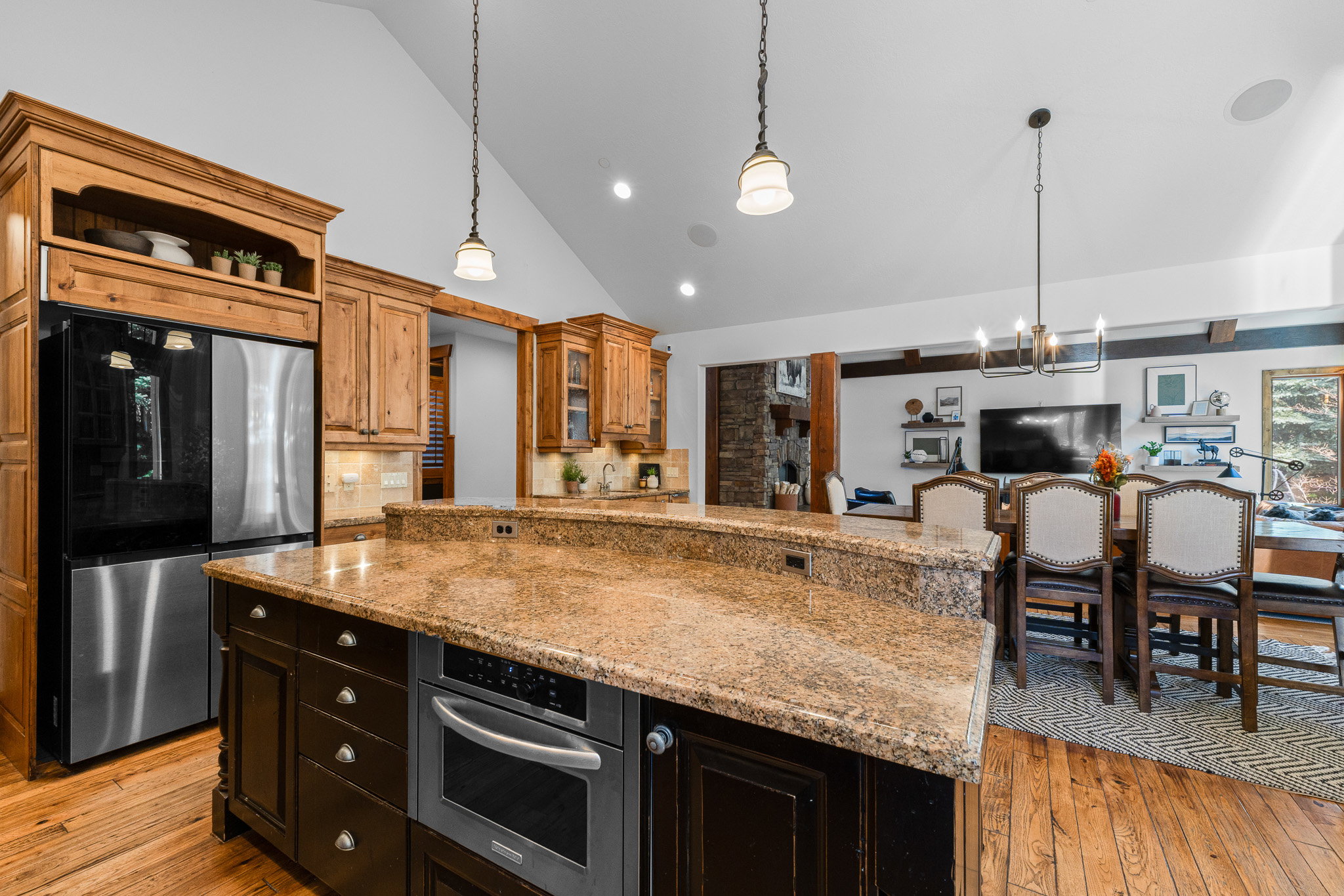 Kitchen island featuring a stone countertop, built-in microwave, and dark wood cabinetry
