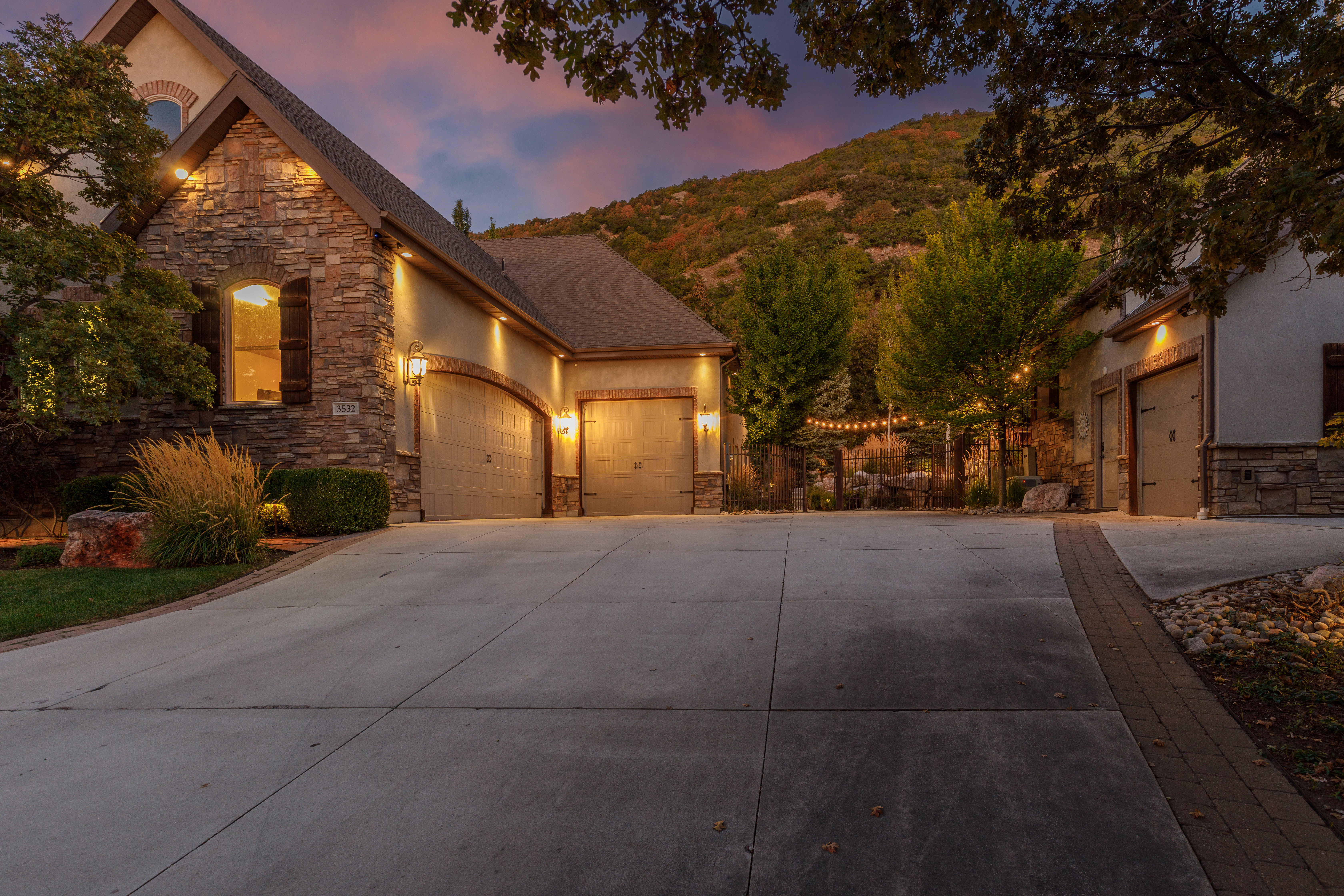 Stone and stucco exterior with multiple garage bays, illuminated by exterior lighting