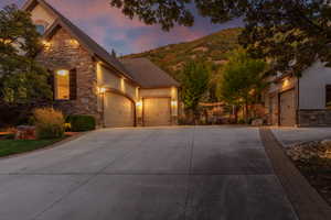 Stone and stucco exterior with multiple garage bays, illuminated by exterior lighting