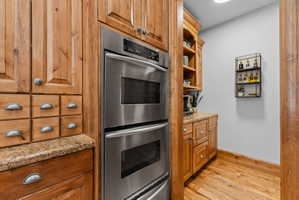Built-in stainless steel double oven complemented by wood-finish cabinetry and granite countertops