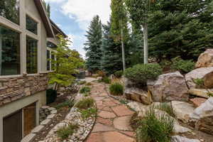 Flagstone pathway bordered by decorative river rock and boulders, leading to a built-in hot tub