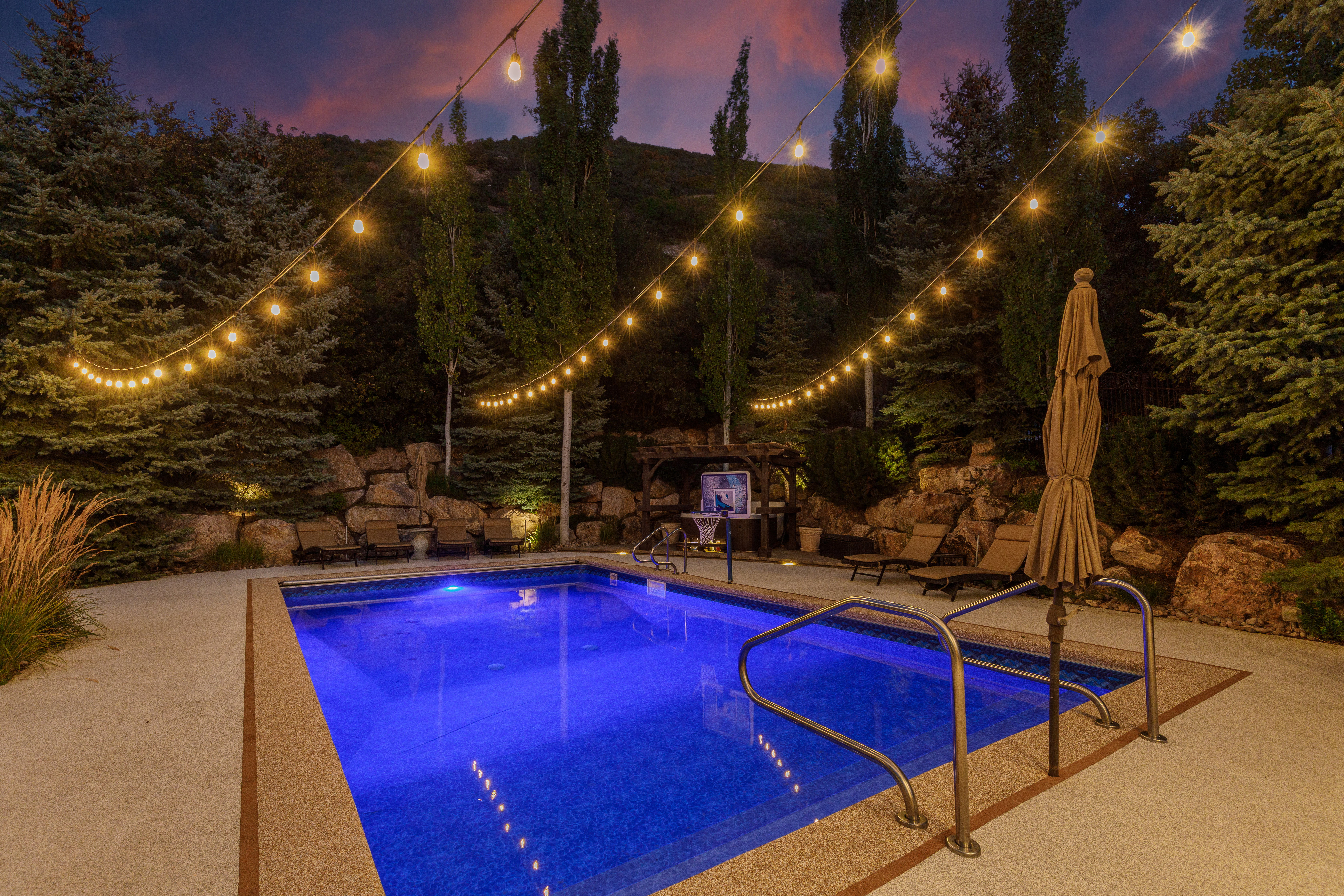 Illuminated swimming pool with integrated lighting, surrounded by a textured concrete patio