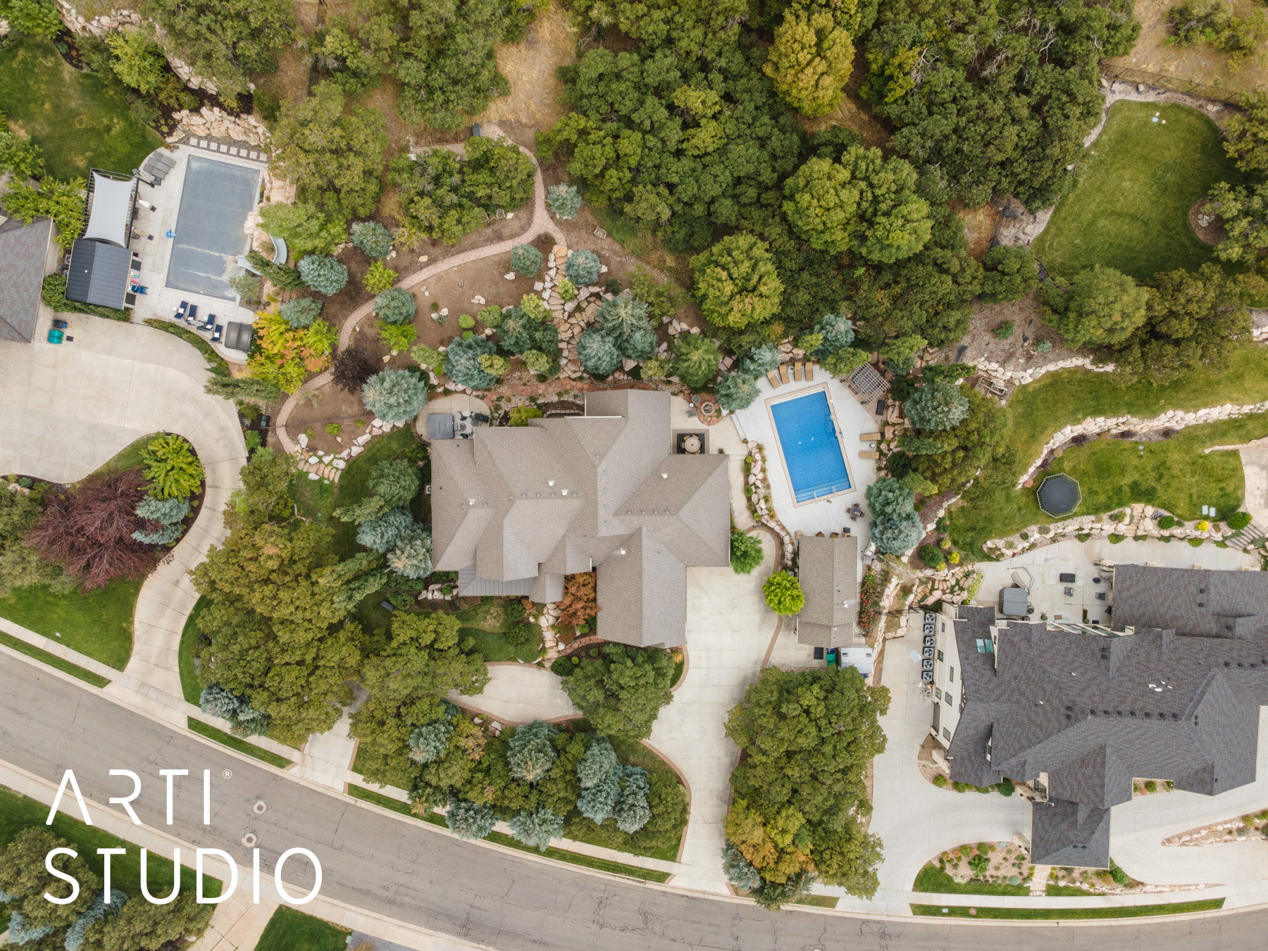 Extensive property featuring a large home with a multi-gabled roof, an in-ground swimming pool, a meandering driveway, and mature landscaping