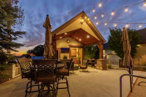 Covered patio with integrated outdoor kitchen, stone accents, recessed lighting, and string lights overhead