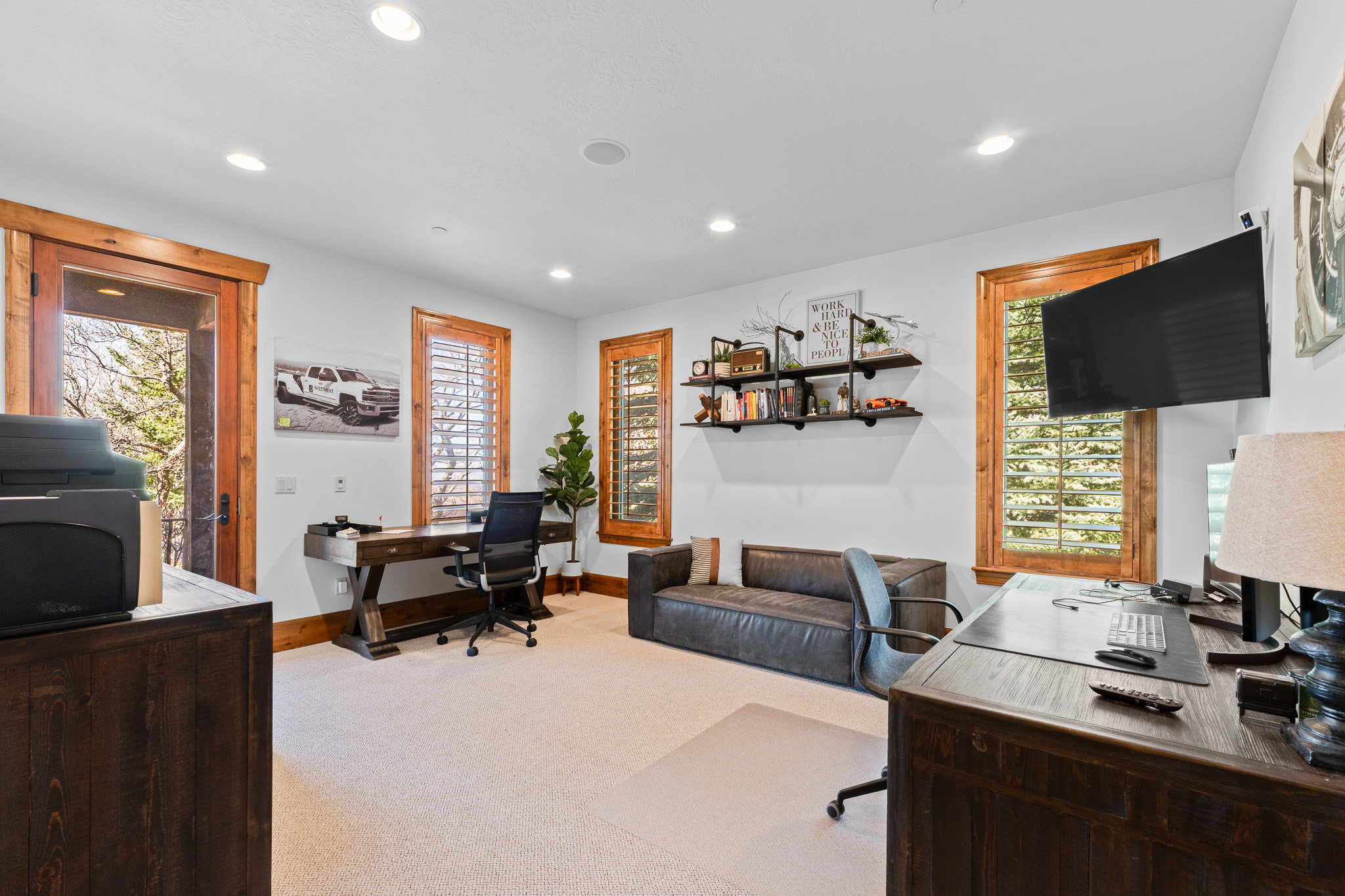 Spacious room featuring light-colored carpeting, recessed lighting, and rich wood-finish trim around windows and doorway