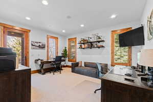 Spacious room featuring light-colored carpeting, recessed lighting, and rich wood-finish trim around windows and doorway