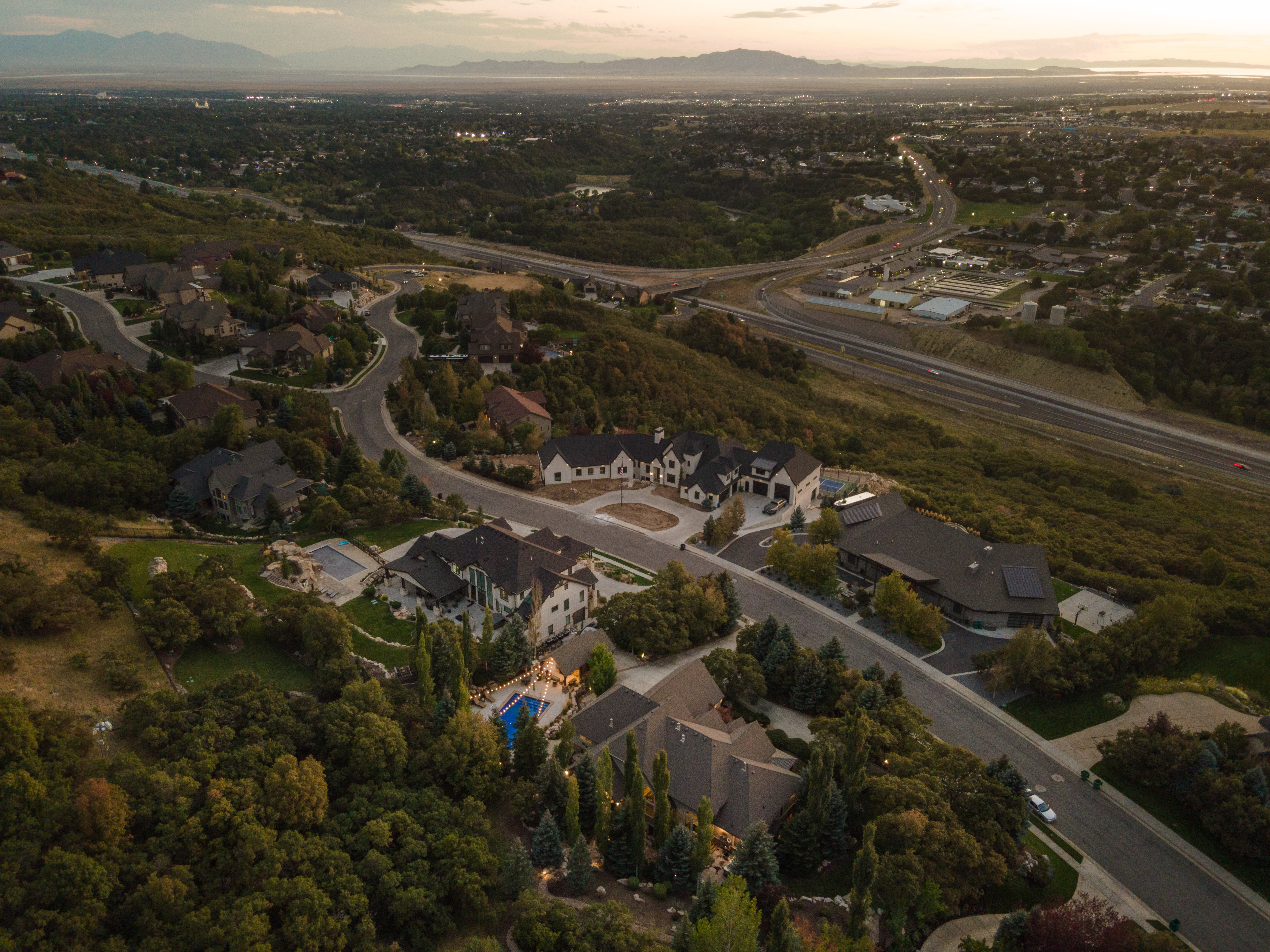 Aerial perspective showcasing a residential community with winding roads, established trees, and mountainous terrain
