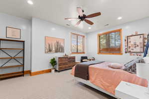 Carpeted room featuring two windows with wood frames, a ceiling fan, and recessed lighting