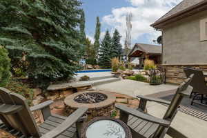 Backyard patio featuring a stone fire pit, concrete and flagstone paving, and a built-in swimming pool