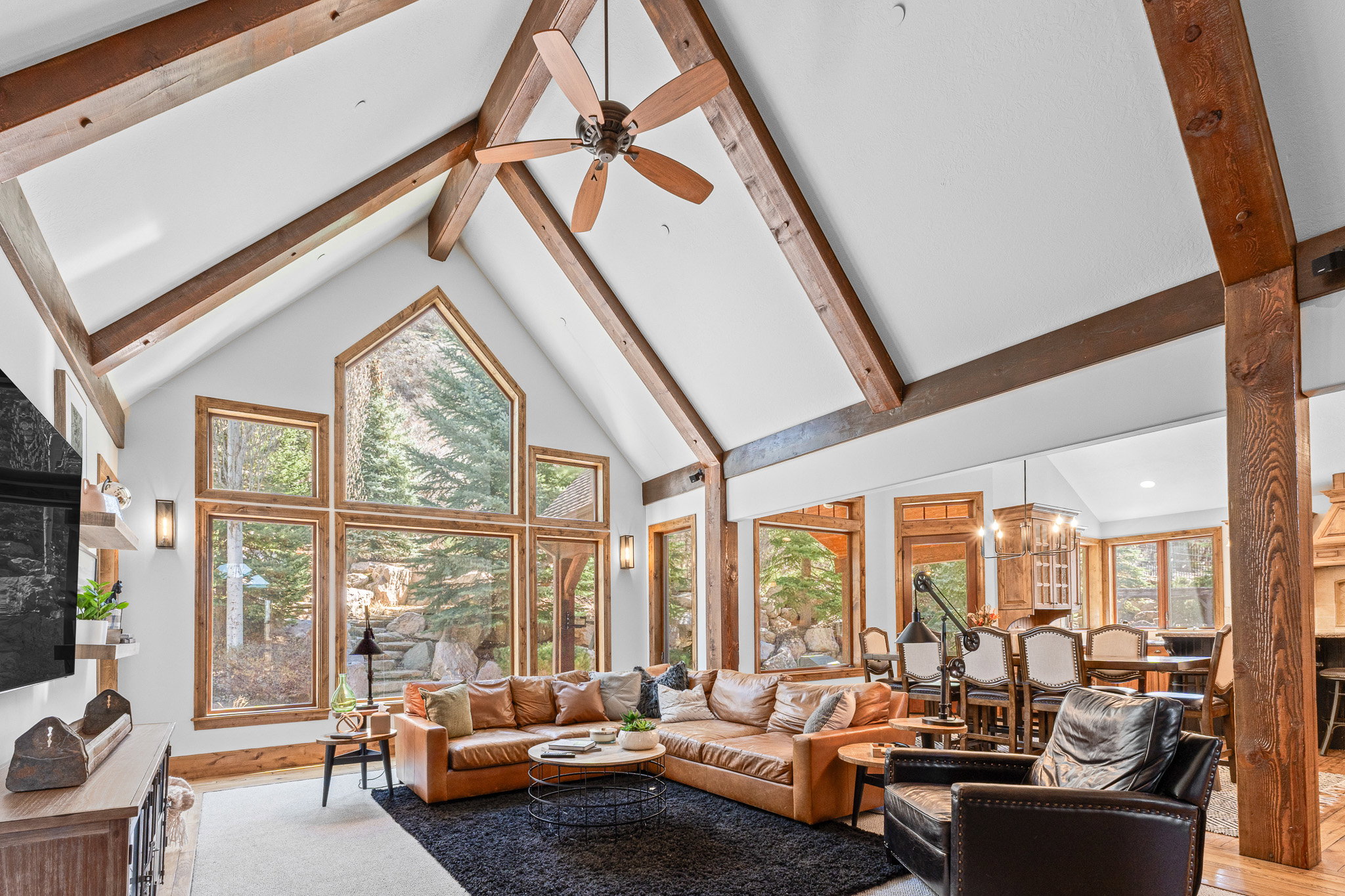 Vaulted ceilings with exposed wood beams, a large picture window, and wood-finish flooring define this living area