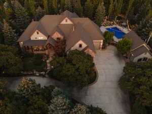 Expansive residence featuring a multi-gabled roofline, stone and stucco exterior, covered front porch, and an outdoor swimming pool