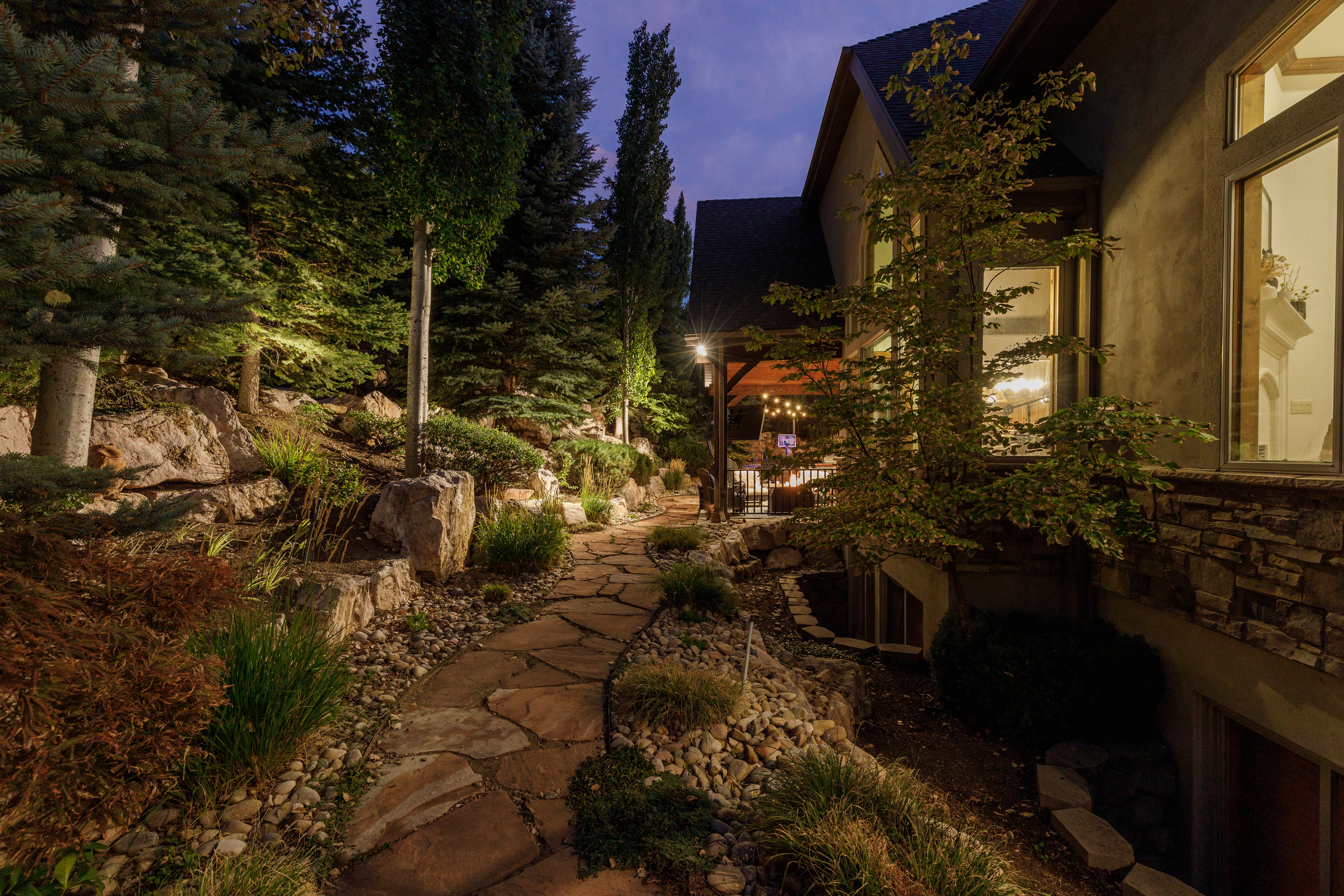 Stone pathway bordered by mature trees and natural rock landscaping