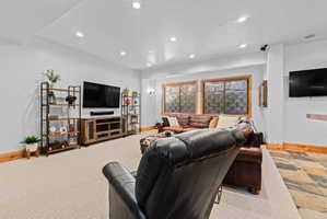 Spacious living area featuring recessed lighting, light-toned carpeting, and a wood-finish media console